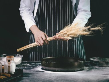 Fırıncı adam mutfakta ekmek hamuru yapmadan önce elinde buğday çivisi, ev yapımı fırın konsepti tutuyor.