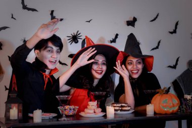 İnsanlar Cadılar Bayramı partisine ürkütücü kostümlerle, korkunç makyajlarla, Cadılar Bayramı partisinde eğlenerek gidiyor.