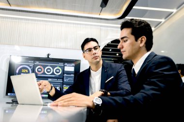 Toplantı odasında dizüstü bilgisayardan bilgi ararken tartışan iki genç iş adamı. Ofis işyerinde birlikte çalışan iş adamları. İş arkadaşları konferans odasında tartışıyorlar..