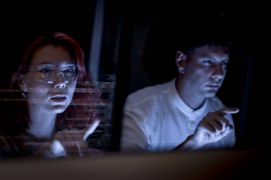 Genç iş adamları gelecekteki ekrana bakıyor ve dijital bilgileri okuyor. Ofiste yüksek teknolojiyle çalışan düşünceli bir veri analisti. İş istatistikleri bir sürü dijital veri ile çalışıyor.