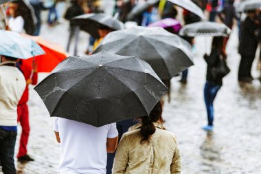 Yağmurlu bir günde dışarıda şemsiyeli insanlar.