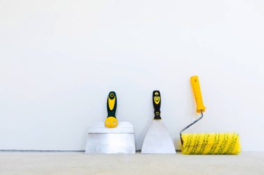Alet boyacısı-sıva ustası. Putty ve duvarları boya. Beyaz arkaplanda sıva araçları.