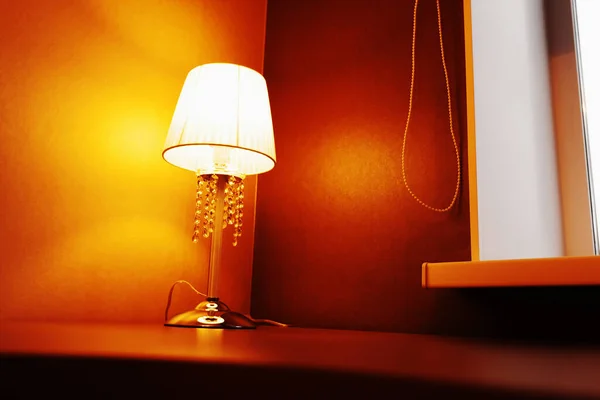 Table lamp by the window. Cozy atmosphere in the house with warm lighting