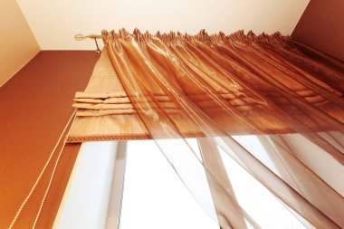 Dairedeki pencerelerde kahverengi perdeler var. Alt görünüm