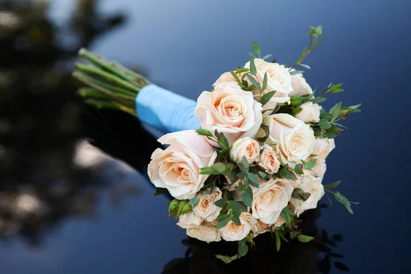 Bouquet of wedding flowers. The groom\'s gift for the bride lies on a dark background. Close-up