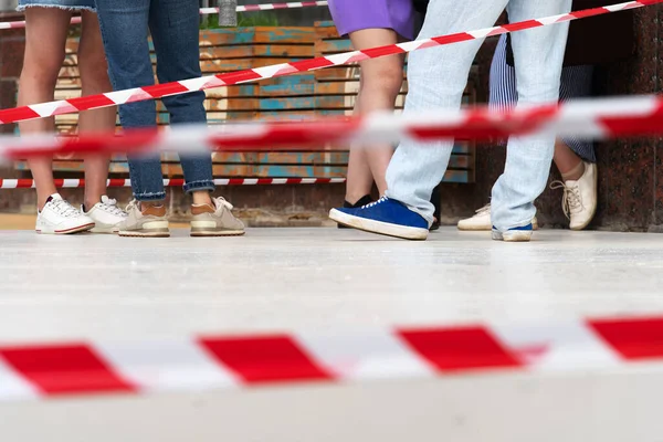 Social distance of people during a pandemic. Fencing with road belts and creating a safety corridor. In the frame, the legs of people in line for groceries. Cropped frame. Selective focus