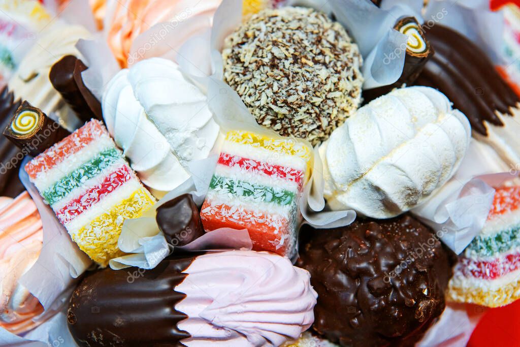 Confectionery of different types close-up. Chocolate-coated sweets sprinkled with coconut and chocolate. View from above