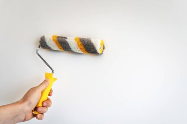 Beyaz arka planda, inşaatçının elinde fırça silindiri var. Boşluğu kopyala