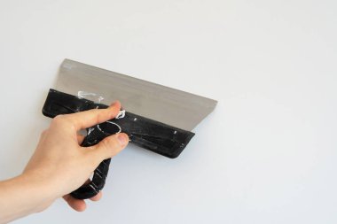 Duvarları alçıcının eliyle beyaz bir duvara yapıştırmak için kullanılan bir spatula. Yakın plan. Boşluğu kopyala