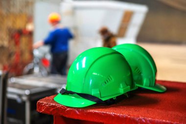 Yapım salonunun arka planında yeşil miğferler var. Metalürji endüstrisinin girişimi. Yakın plan.