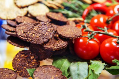 Fındıklı çavdar kurabiyeleri ve kırmızı domateslerle süslenmiş susam tohumları. Un ve sebzelerden yapılan sağlıklı yiyecekler. Yakın plan.