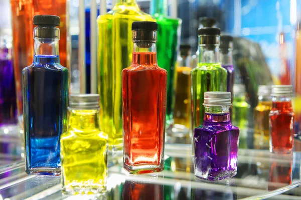 Multi-colored bottles with alcohol on a glass shelf. Collection of alcoholic drinks in a minibar. Close-up