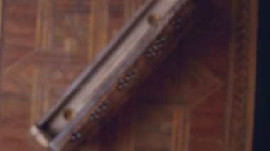 Tütsü (tütsü çubukları) eşsiz bir ahşap kutuda sigara içer. Odak noktası dumandır. Kutu ahşap bir masa üzerinde el yapımı. Saat yönünde döner. Yukarıdan görüntüle.