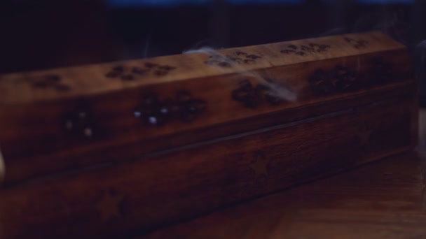 L'encens (bâtonnets d'encens) fume dans une boîte en bois unique avec une étoile. La fumée sort des trous. La boîte est sur une table faite à la main. Gros plan. Dans le sens inverse des aiguilles d'une montre. Focus sur la fumée.