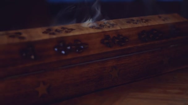L'encens (bâtonnets d'encens) fume dans une boîte en bois unique avec une étoile. La fumée sort des trous. La boîte est sur une table faite à la main. Gros plan. Dans le sens inverse des aiguilles d'une montre. Focus sur la fumée.Mouvement cyclique trois tours.