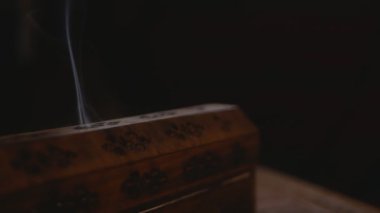 Tütsüden çıkan duman, yıldızlı eşsiz bir ahşap kutudan çıkar. Yakın plan. Duman kutu deliklerinden çıkıyor. Saat yönünde dön. Dumana odaklan. Siyah arkaplan.