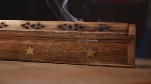 Des bouffées de fumée s'écoulent d'une boîte à encens en bois unique avec une étoile. La fumée sort des trous. Gros plan. Rotation cyclique dans le sens antihoraire.Vue latérale. Focus sur la fumée.