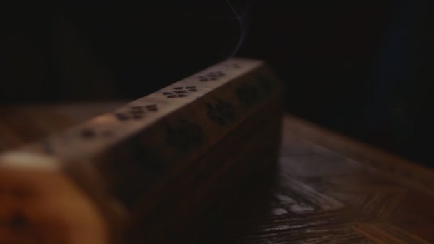 Des couches de fumée s'écoulent d'une boîte d'encens en bois unique, demi-tour. La fumée sort des boîtes avec des trous. Focus sur le bien-être. Fond noir.