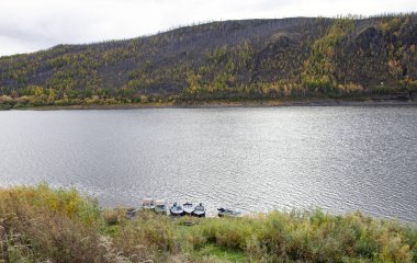 Podkamennaya Tunguska nehri ve sonbaharda kıyıya yakın tekneler. Sibirya taygası ve Tunguska nehrinin kıyıları Tura köyü yakınlarında..