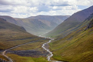 Asya 'nın yüksek dağlarındaki bir geçitten geçmek zor toprak yol. Alp yolu geçitten geçiyor..