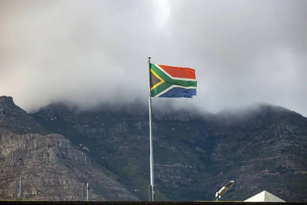 在开普敦桌山的背景下俯瞰南非共和国国旗的景色 南非的国旗在风中飘扬 背景是大雾和海角的云山 — 图库照片