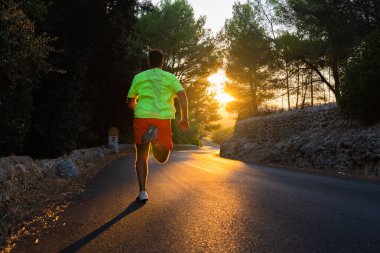 Çam ormanının ortasındaki bir yolun manzarası Güzel altın gün batımı ve odak dışı adam koşuyor