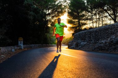 Genç İspanyol bir adam, çam ormanının ortasında eğimli bir yolda altın bir gün batımında koşar. Adam çarpıcı ve spor kıyafetler giyer.