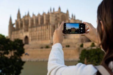 Açık tenli genç kız tatilde Palma de Mallorca katedralinin fotoğrafını çekiyor..