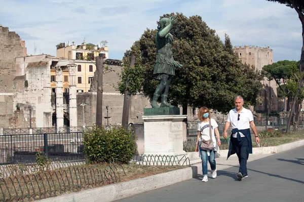 Roma, İtalya - Haziran 02 2020 İtalya yeniden açılıyor, 3. aşamaya başlayın. Roma, İtalya 'da Colosseum (Colosseo) yakınlarındaki Fori Imperiali caddesinde koruyucu maskeler takan insanlar yürüyor.