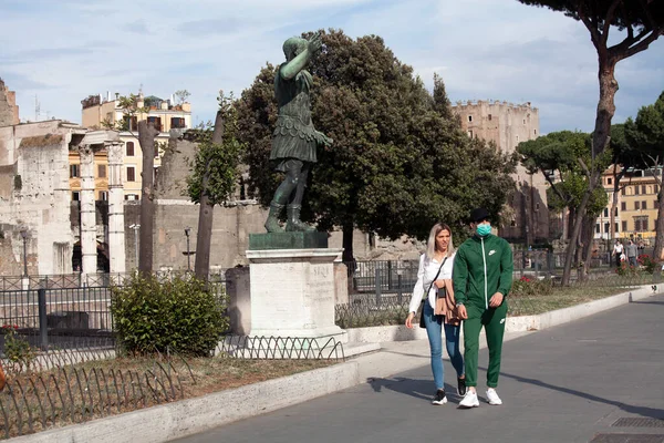 Roma, İtalya - Haziran 02 2020 İtalya yeniden açılıyor, 3. aşamaya başlayın. Roma, İtalya 'da Colosseum (Colosseo) yakınlarında Fori Imperiali caddesinde yürüyen koruyucu maskeli bir çift görülüyor..