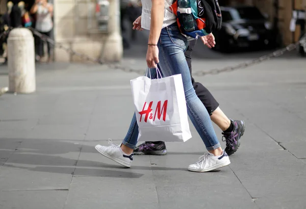 ROME, ITALY - 17 Ekim 2016: Pedestrian, İtalya 'nın ana alışveriş caddesi Via del Corso' da H & M alışveriş çantasıyla yürüyor