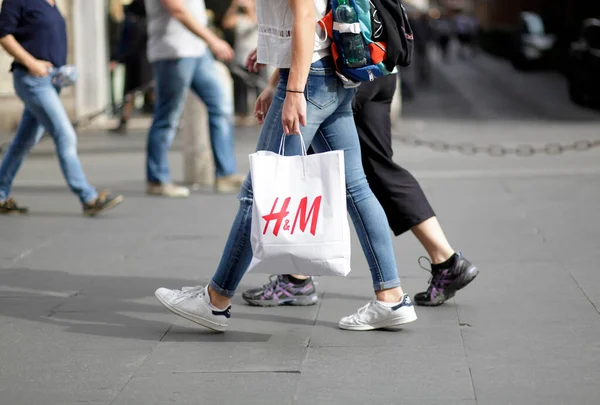 ROME, ITALY - 17 Ekim 2016: Pedestrian, İtalya 'nın ana alışveriş caddesi Via del Corso' da H & M alışveriş çantasıyla yürüyor