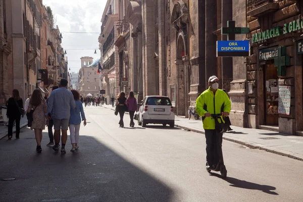 ROME, ITALY - 01.01.2020: Bir adam İtalya, Via del Corso 'da koruyucu yüz maskesi takan elektrikli scooter sürüyor.
