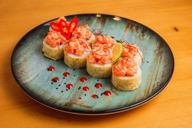 Üstünde balık olan taze maki, mavi bir tabakta servis edilir.