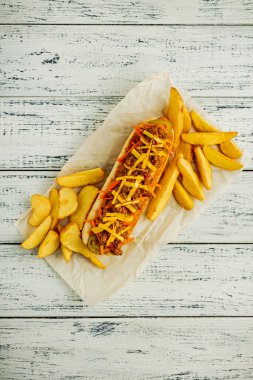 Kıyma, sosis ve biberli, kızarmış patates garnitürlü sosisli sandviç. Beyaz ahşap masa