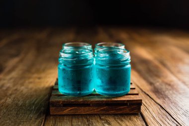 Mavi renkli alkolikler ya da ahşap masada içki içenler.