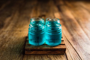 Mavi renkli alkolikler ya da ahşap masada içki içenler.