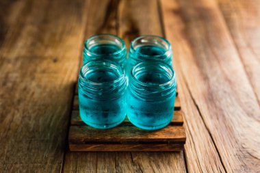 Mavi renkli alkolikler ya da ahşap masada içki içenler.