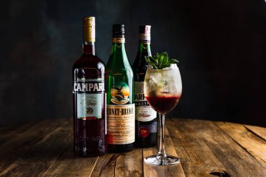 Belarus, Minsk - 12.03.2020: nane, bir şişe Campari, Fernet-Branca ve Carpano Classico vermut ile süslenmiş şarap kadehinde ferahlatıcı katmanlı buzlu kokteyl