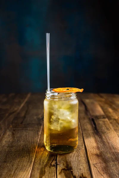 Kavanozda taze buzlu kokteyl, pipet ve kuru turuncu tekerlekle.