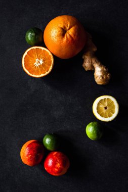 Meyve, greyfurt, portakal, limon, kireç, kan portakalı ve zencefil. Gri arkaplanda karanlık ve karamsar bir fotoğraf. Boşluğu kopyala.