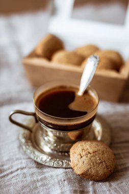 Güzel cam bir fincan kahvenin yakın plan fotoğrafı, cam tutacağında metal bir fincan ve karton bir kutuda kurabiyeler.
