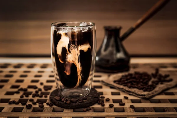 加奶到一大杯冰咖啡 咖啡豆周围 Cezve 木制桌子和木制背景 横向照片 — 图库照片