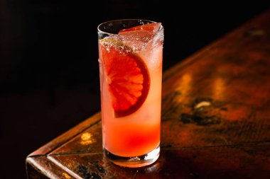 Buzlu ve bir parça portakalla süslenmiş bir viski bardağında portakal suyu kokteyli.