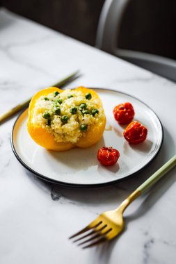 Kuskus, yeşil bezelye, peynir ve vişneli domatesle doldurulmuş fırında sarı biber.