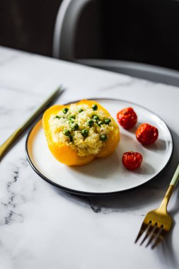 Kuskus, yeşil bezelye, peynir ve vişneli domatesle doldurulmuş fırında sarı biber.