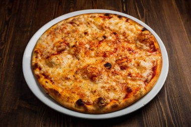 Güzel kabuklu peynirli pizza, ahşap arka plan, sade anahtar.