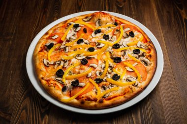 Mantar, sarı biber, siyah zeytin, domates ve peynirli pizza, ahşap arka plan, sade anahtar