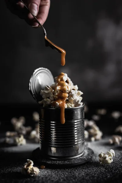 Adicionando Caramelo Cima Pipoca Salgada Uma Lata Aço Fundo Escuro — Fotografia de Stock