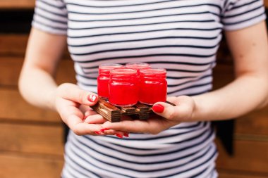 Elinde tahta tahta bir tahta, elinde 4 kırmızı nişancı ya da içki tutan bir kız.